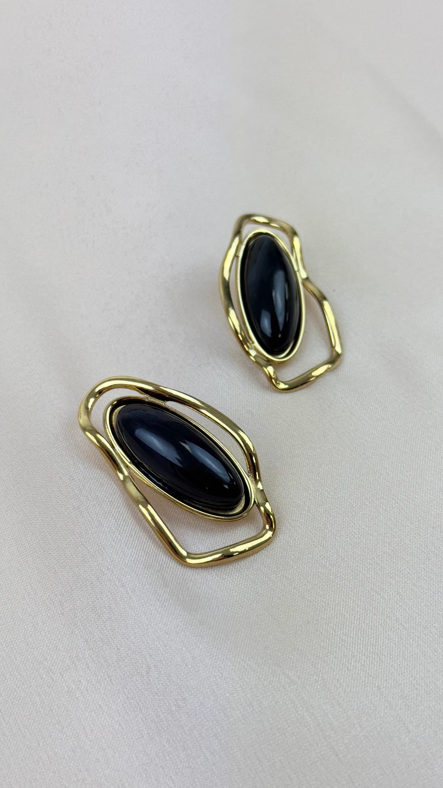 Brincos aço dourado assimétrico com centro em preto