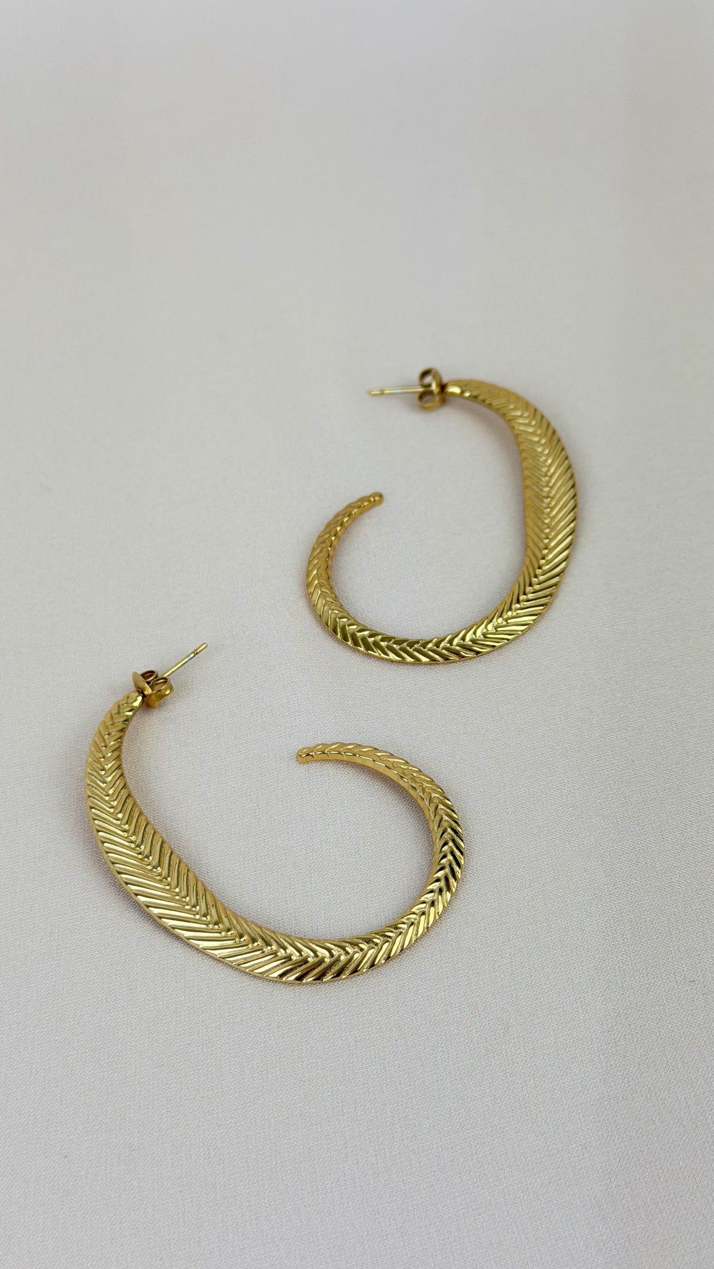 Brincos aço dourado formato pena fina